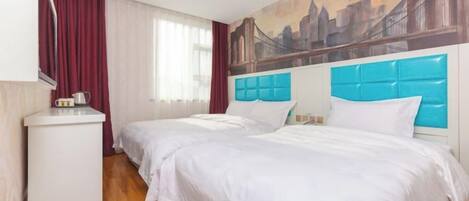 Una habitación de hotel con dos camas, un escritorio y un cuadro de un paisaje urbano en la pared.