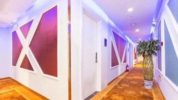 A hotel hallway with patterned carpet, white walls, and doors with large X-shaped cutouts. - Super 8 Hotel (Beijing You'anmen Outer Street) (Beijing)