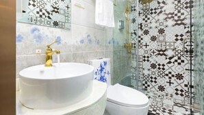 A bathroom with a white sink, gold faucet, and a toilet. The walls are tiled with a geometric pattern. - Super 8 Hotel (Beijing You'anmen Outer Street) (Beijing)