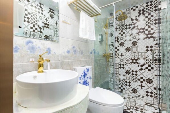 A bathroom with a white sink, gold faucet, and a toilet. The walls are tiled with a geometric pattern. - Super 8 Hotel (Beijing You'anmen Outer Street) (Beijing)