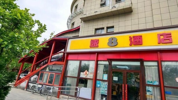 Un hotel con fachada roja y amarilla, una escalera que lleva a un nivel superior y una bicicleta estacionada afuera.