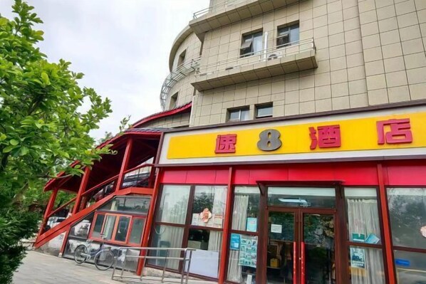 A hotel with a red and yellow facade, a staircase leading to an upper level, and a bicycle parked outside. - Super 8 Hotel (Beijing You'anmen Outer Street) (Beijing)