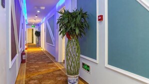 A hallway with a patterned carpet, a potted plant, and a fire alarm. - Super 8 Hotel (Beijing You'anmen Outer Street) (Beijing)