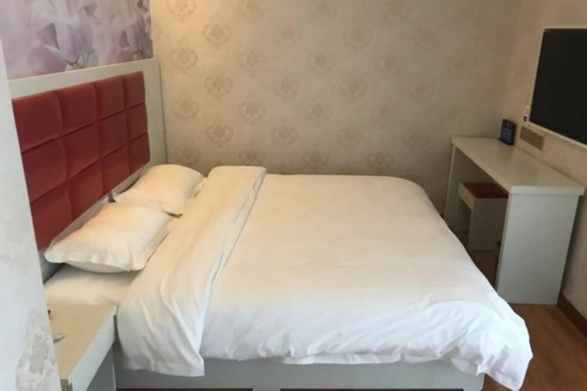 Una cama individual con cabecera, una mesita de noche y un pequeño escritorio con silla.