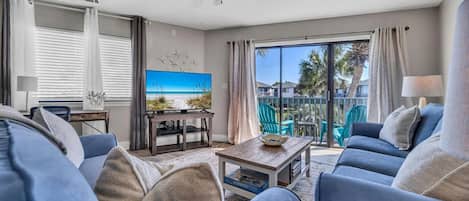 A living room with a TV, blue sofas, a coffee table, and a ceiling fan.
