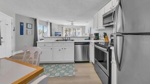 Une cuisine moderne avec des armoires blanches, des appareils en acier inoxydable et une table à manger en bois.