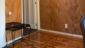 Et værelse med træpaneler, en dør, et lille bord og en lampe.