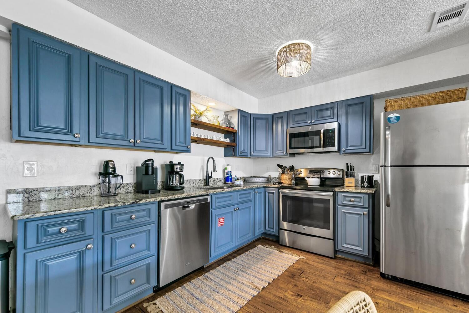 Una cocina moderna con armarios azules, electrodomésticos de acero inoxidable y encimera de granito.
