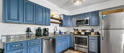 Una cocina moderna con armarios azules, electrodomésticos de acero inoxidable y encimera de granito.