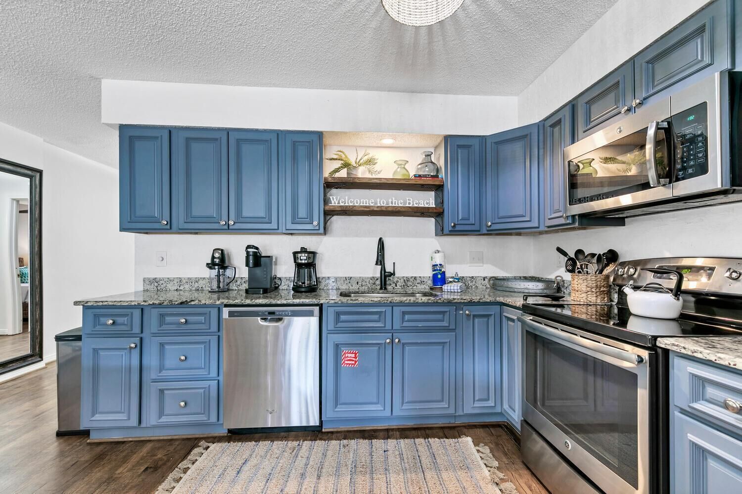 A kitchen with blue cabinets, stainless steel appliances, and a granite countertop.