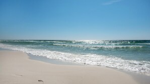 Ein Strand mit Fußabdrücken im Sand und ankommenden Wellen.