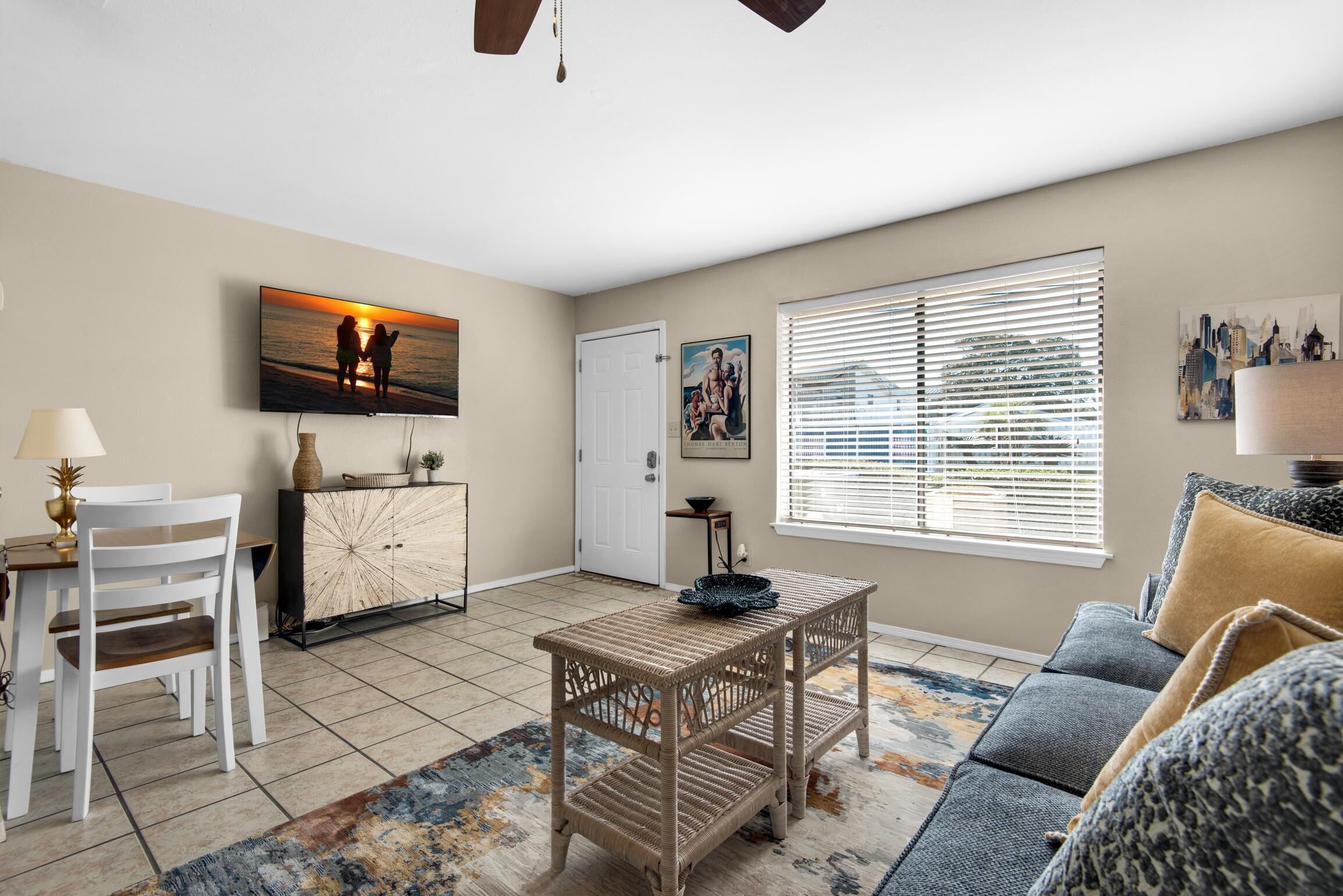 A living room with a dining area, a sofa, a coffee table, and a TV mounted on the wall.