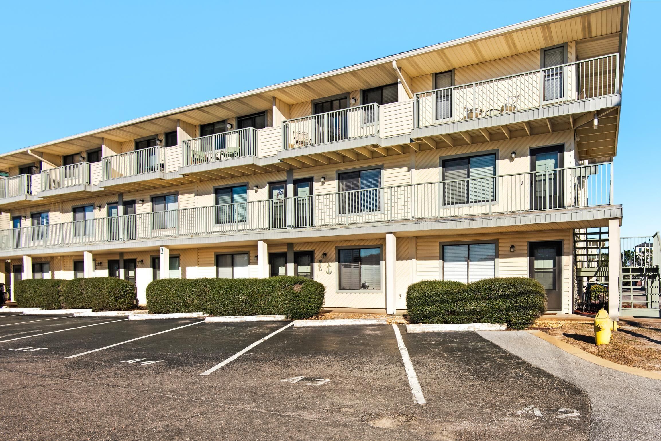 A multi-story hotel with a parking lot in front.