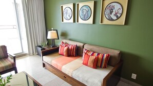 Un salon avec un canapé, une table d’appoint et trois œuvres d’art encadrées accrochées au mur.