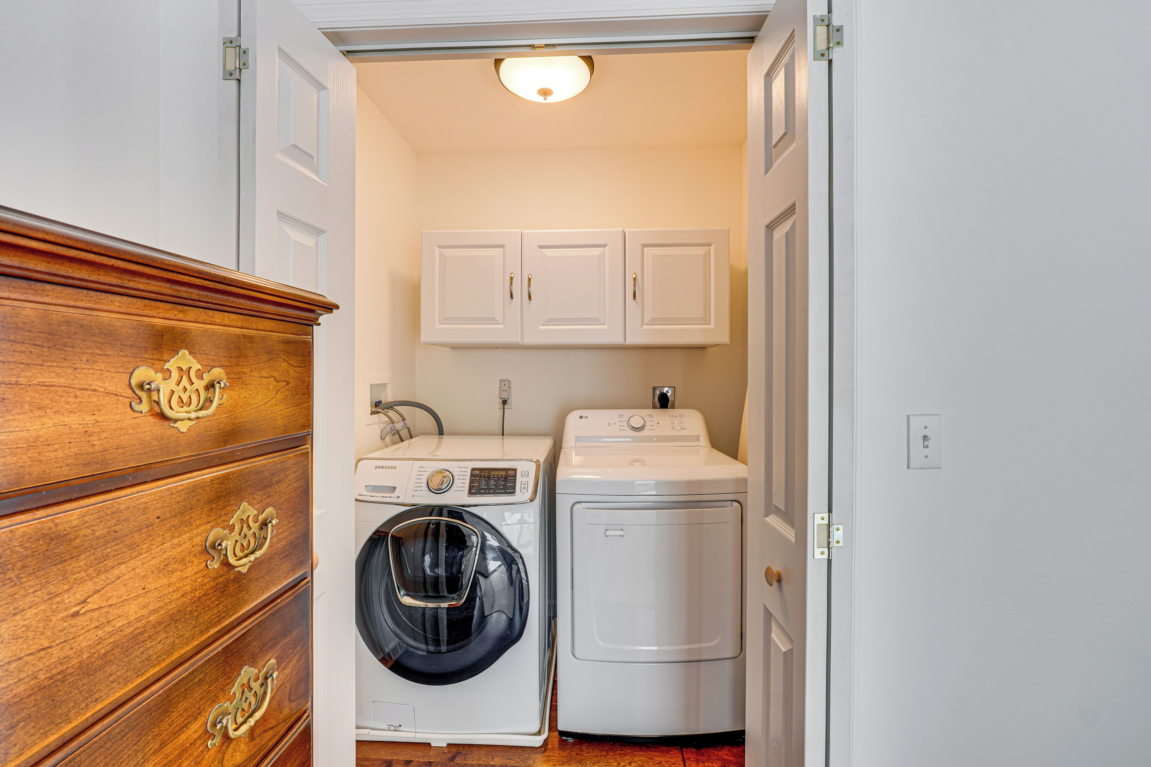 A laundry room with a wooden dresser, a washing machine, and a dryer.
