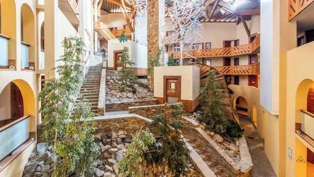 A multi-level atrium with a central staircase, stone walls, and wooden railings. - Tikal  (Les Belleville)