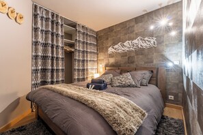 Ein modernes Schlafzimmer mit einem großen Bett, einem Kleiderschrank und einer Wanddekoration.