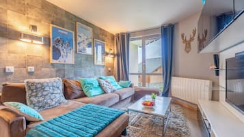 Habitación triple Deluxe, vista a la montaña | Área de sala de estar | Televisión LED