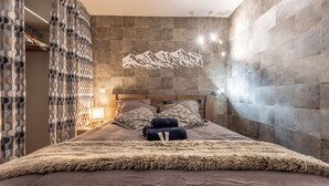 A modern bedroom with a large bed, patterned curtains, a mountain wall art, and a cozy atmosphere. - Tikal  (Les Belleville)