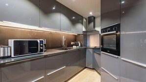 A modern kitchen with stainless steel appliances, including a microwave, toaster, and oven. - Tikal  (Les Belleville)