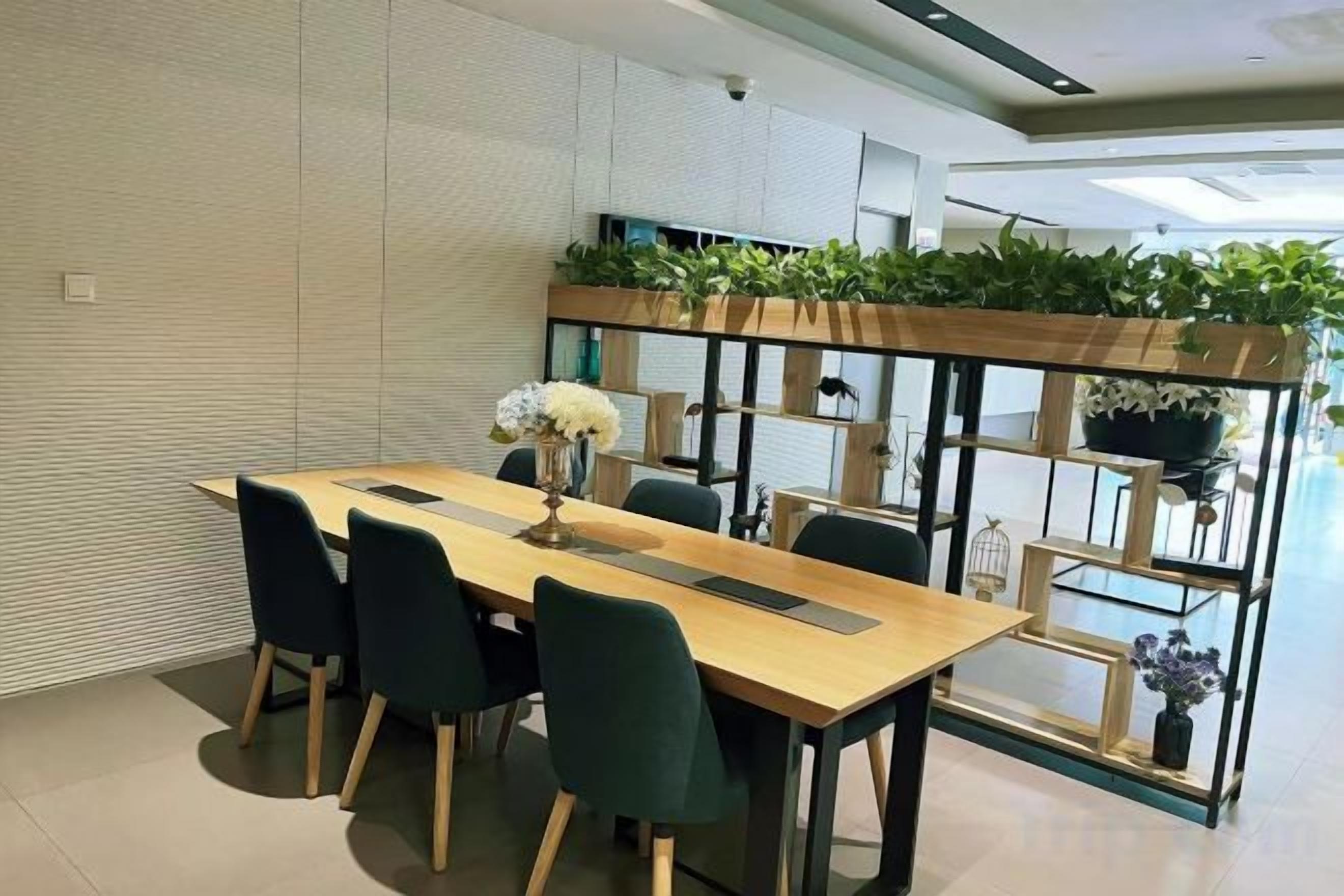 A modern dining area with a long table, chairs, and a plant shelf.