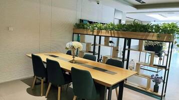 A modern dining area with a long table, chairs, and a plant shelf.