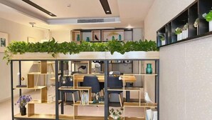 A modern office space with a glass partition, wooden desks, and shelves with decorative items. - Homeinn Selected Hotel (Shanghai Lin-gang Ocean Park Dishui Lake) (Shanghai)