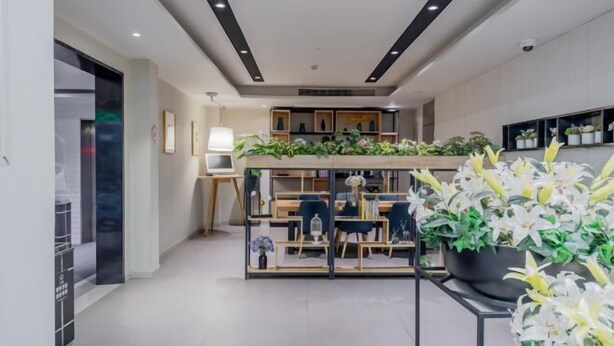 A modern interior with a reception desk, seating area, and a display of plants. - Homeinn Selected Hotel (Shanghai Lin-gang Ocean Park Dishui Lake) (Shanghai)