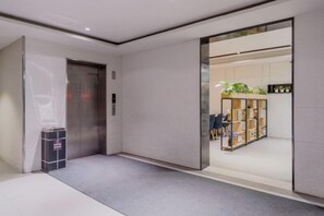 A modern elevator with a glass door, a small trash bin, and a carpeted floor. - HomeInn Seleted Hotel (Shanghai Planetarium Dishui Lake Metro Station Branch) (Shanghai)