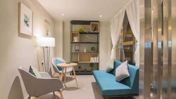 A modern living room with a sofa, two chairs, a small table, and a bookshelf.