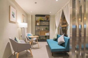 Een moderne woonkamer met een bank, twee fauteuils, een salontafel en een boekenkast.
