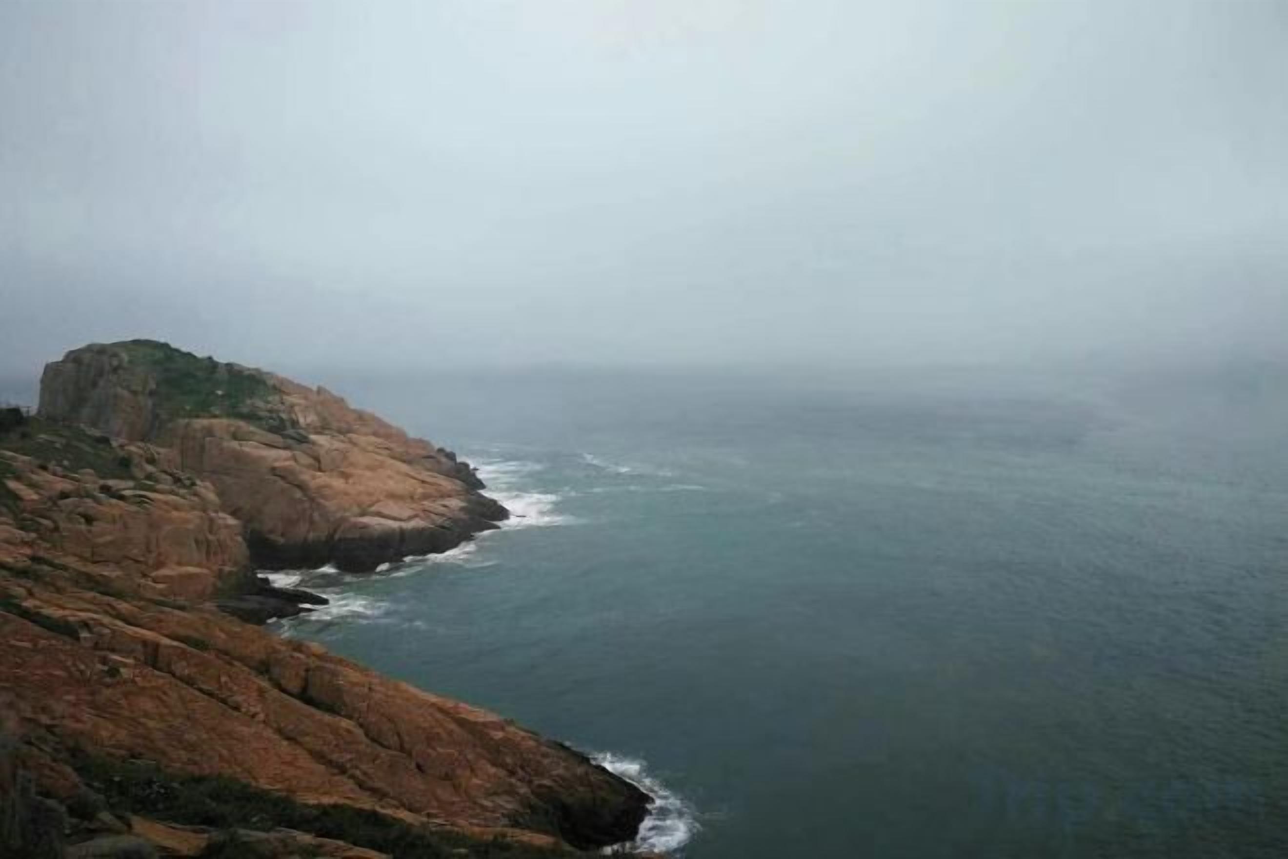 Un paysage côtier avec une falaise rocheuse et l’océan.