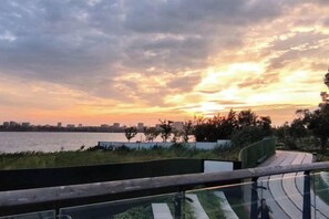 A sunset view from a balcony with a railing, overlooking a body of water and a distant city skyline. - HomeInn Seleted Hotel (Shanghai Planetarium Dishui Lake Metro Station Branch) (Shanghai)