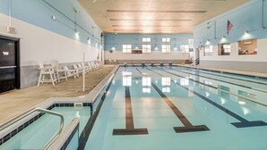 Ein Schwimmbecken mit mehreren Bahnen, einem Rettungsschwimmerstuhl und einem Notausgangsschild.