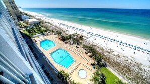 A resort with a beach view, multiple swimming pools, and a sandy beach with umbrellas.