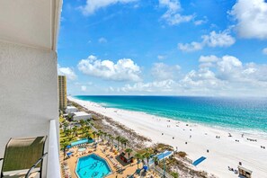 A beach resort with a swimming pool, beach umbrellas, and a view of the ocean. - The Summit 1209 (Panama City Beach)