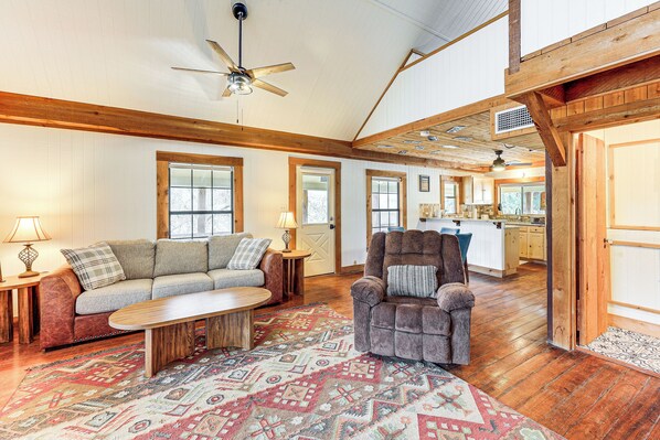 A spacious living room with a wooden ceiling, a sofa, a chair, and a coffee table. - Fire Pit, Views: Peaceful Texas Hill Country Cabin (Tarpley)