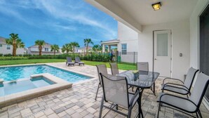 Um pátio com piscina, móveis de exterior e vista para casas vizinhas.