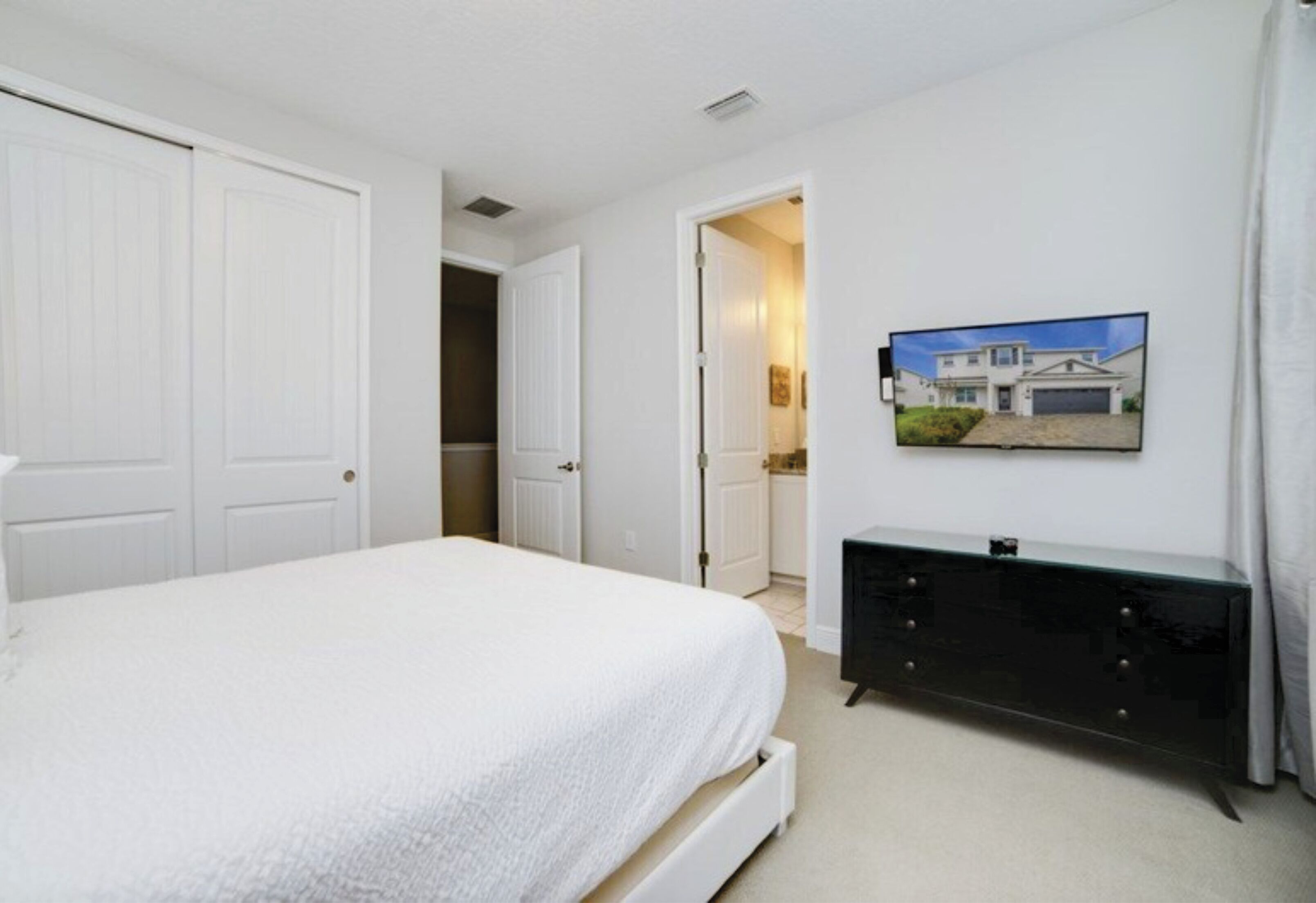 Une chambre à coucher avec un lit, une commode et un téléviseur fixé au mur.