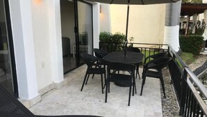 An outdoor patio with a round table and chairs, a large umbrella, and a view of the surrounding area. - The Grand Mayan at Vidanta! 1 BR studio! (Acapulco)
