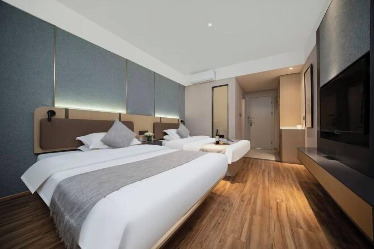 Une chambre d’hôtel moderne équipée de deux lits, d’une télévision et d’un mini-bar.