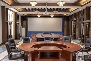 Une salle de confĂ©rence Ă©quipĂ©e dâune table ronde, de plusieurs chaises, dâun grand Ă©cran et dâun projecteur.