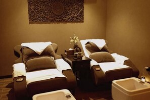 A room with two massage chairs, a small table with a vase of flowers, and a sink. - Shiji Xinghe Hotel (Huangshan Tunxi Old Street) (Huangshan City)