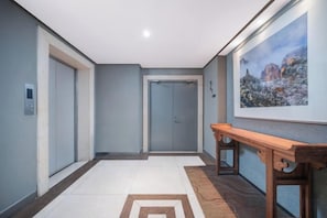 Um corredor com um banco de madeira, uma porta e um quadro pendurado na parede.