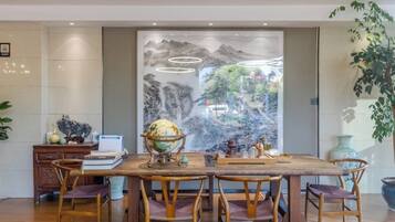A dining area with a wooden table, chairs, a globe, and a decorative wall with a mountainous landscape.