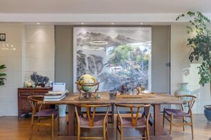 A dining area with a wooden table, chairs, a globe, and a decorative wall with a mountainous landscape. - Shiji Xinghe Hotel (Huangshan Tunxi Old Street) (Huangshan City)