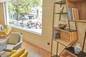 Un intérieur moderne avec un coin salon, une grande fenêtre et une bibliothèque en bois.