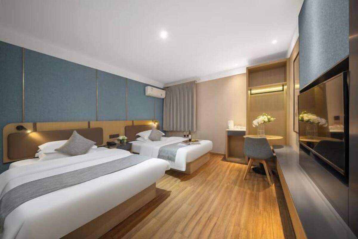 Une chambre d’hôtel avec deux lits, un bureau, une chaise, une télévision et un miroir.