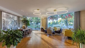 Ein modernes Interieur mit Holzboden, einem Essbereich und Sitzgelegenheiten mit Blick auf Grünflächen.