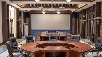 A conference room with a large oval table, multiple chairs, a projector screen, and a large window.